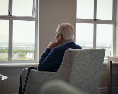 Older Man Sitting on Armchair Looking Out the Window