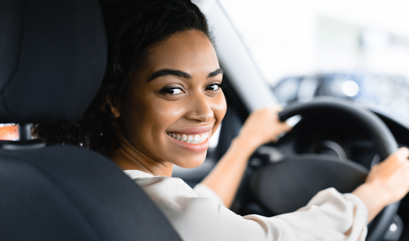 Young Woman Driver Looking Into Back Seat While in Driver's Seat