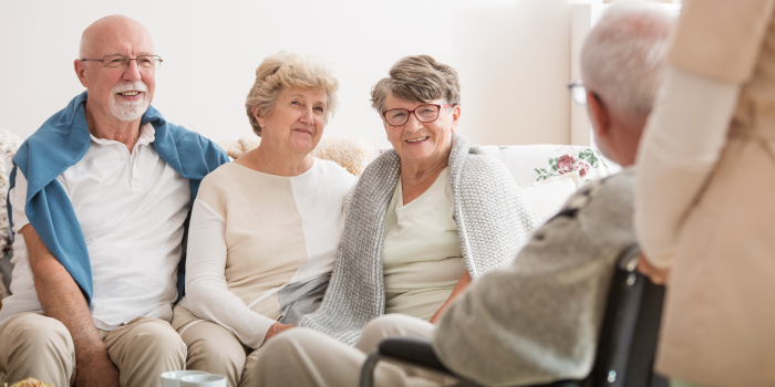 Group of Smiling Older Adults Sitting on Couch in a Common Room