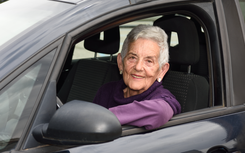 Smiling Older Woman Sitting in the Driver's Seat of Car