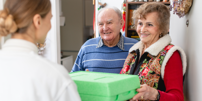 Young Woman Delivering a Boxed Meal to an Older Couple