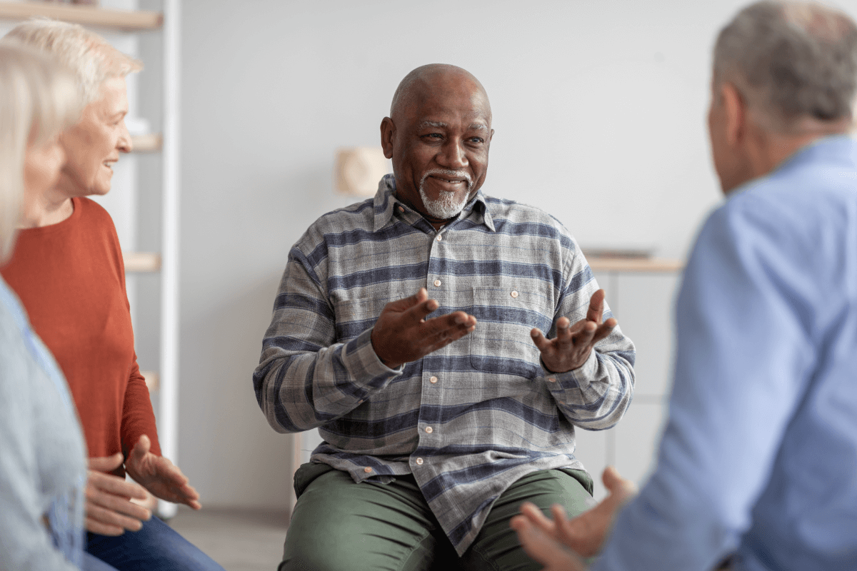 Older Man Having Conversation with Other Older Adults in a Support Group Session