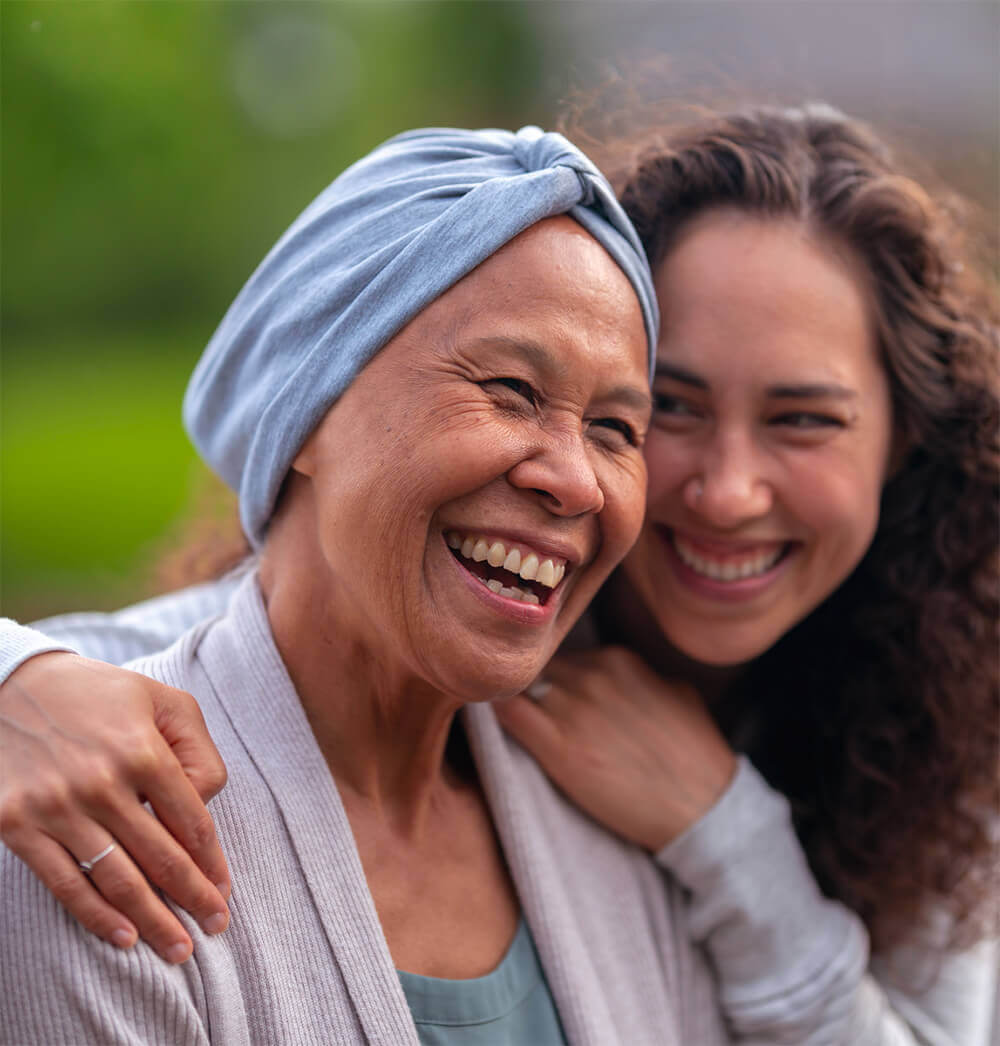 Younger Woman Hugging Older Woman, Both Smiling.